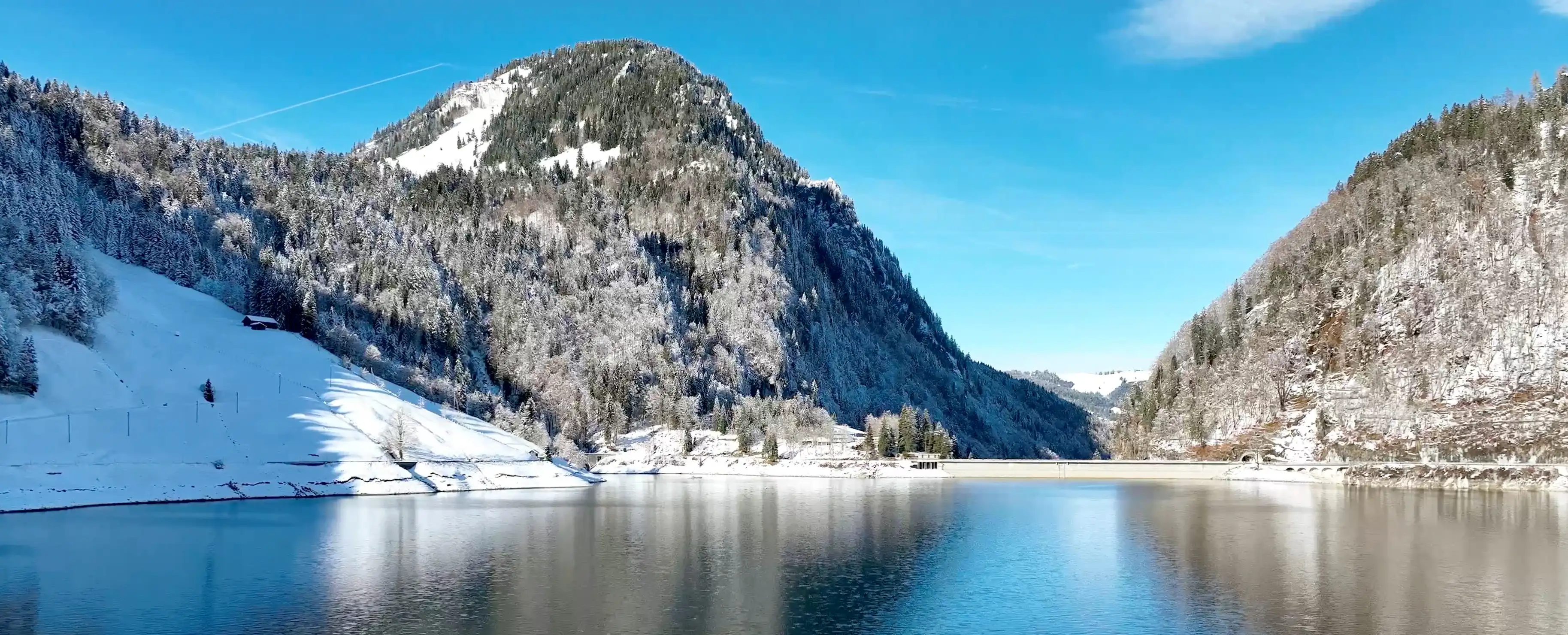 Der Wägitalsee im winterlichen Schnee, umgeben von schneebedeckten Bergen